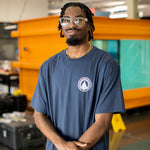Man wearing a navy blue t-shirt with the WHOI Classic Seal Logo on the front left chest.
